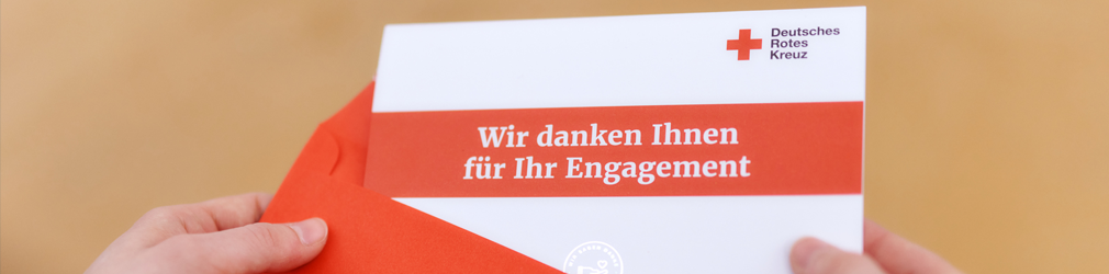 Hände die einen Brief aus einem roten Umschlag ziehen